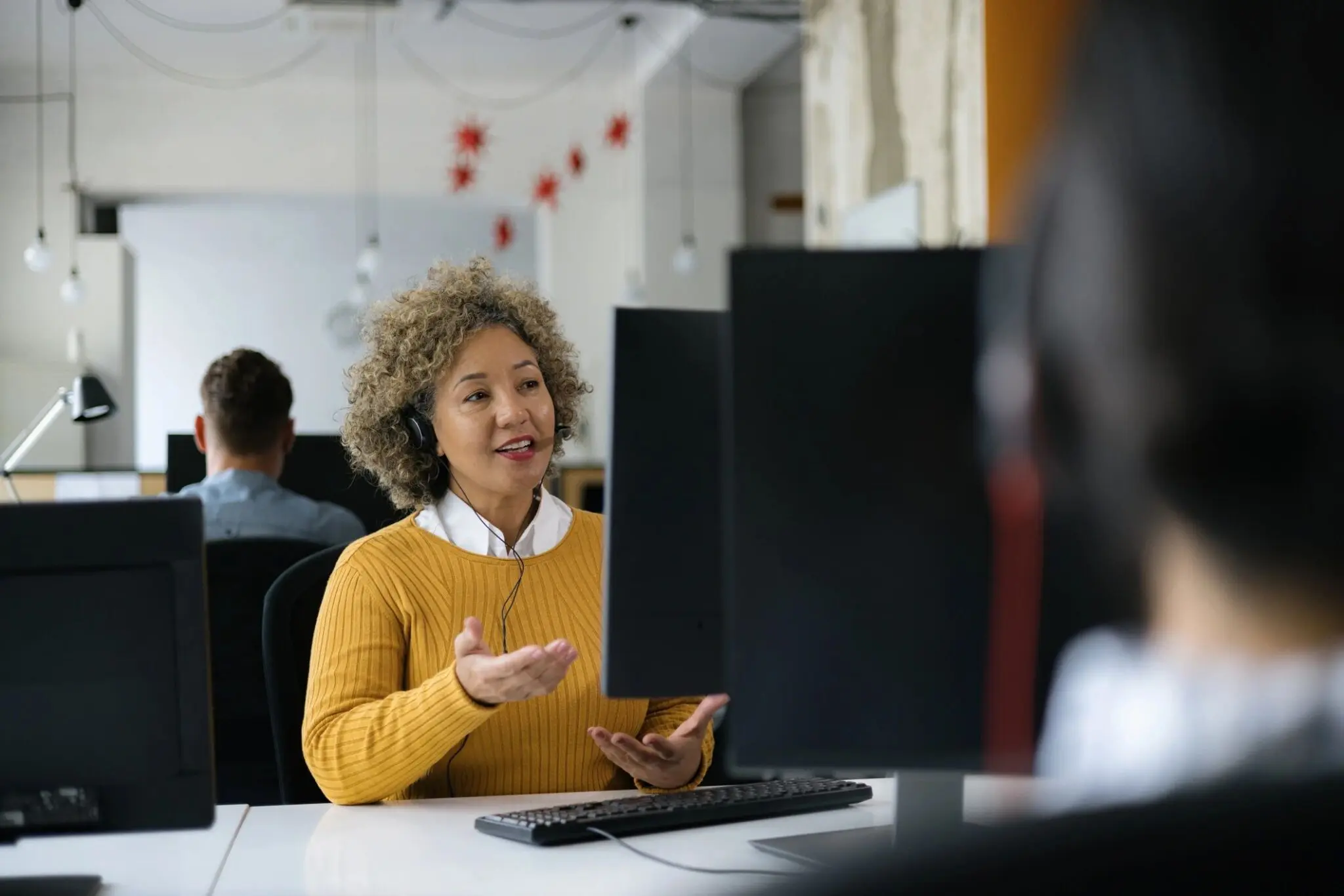 Woman in office talking, wearing headset.