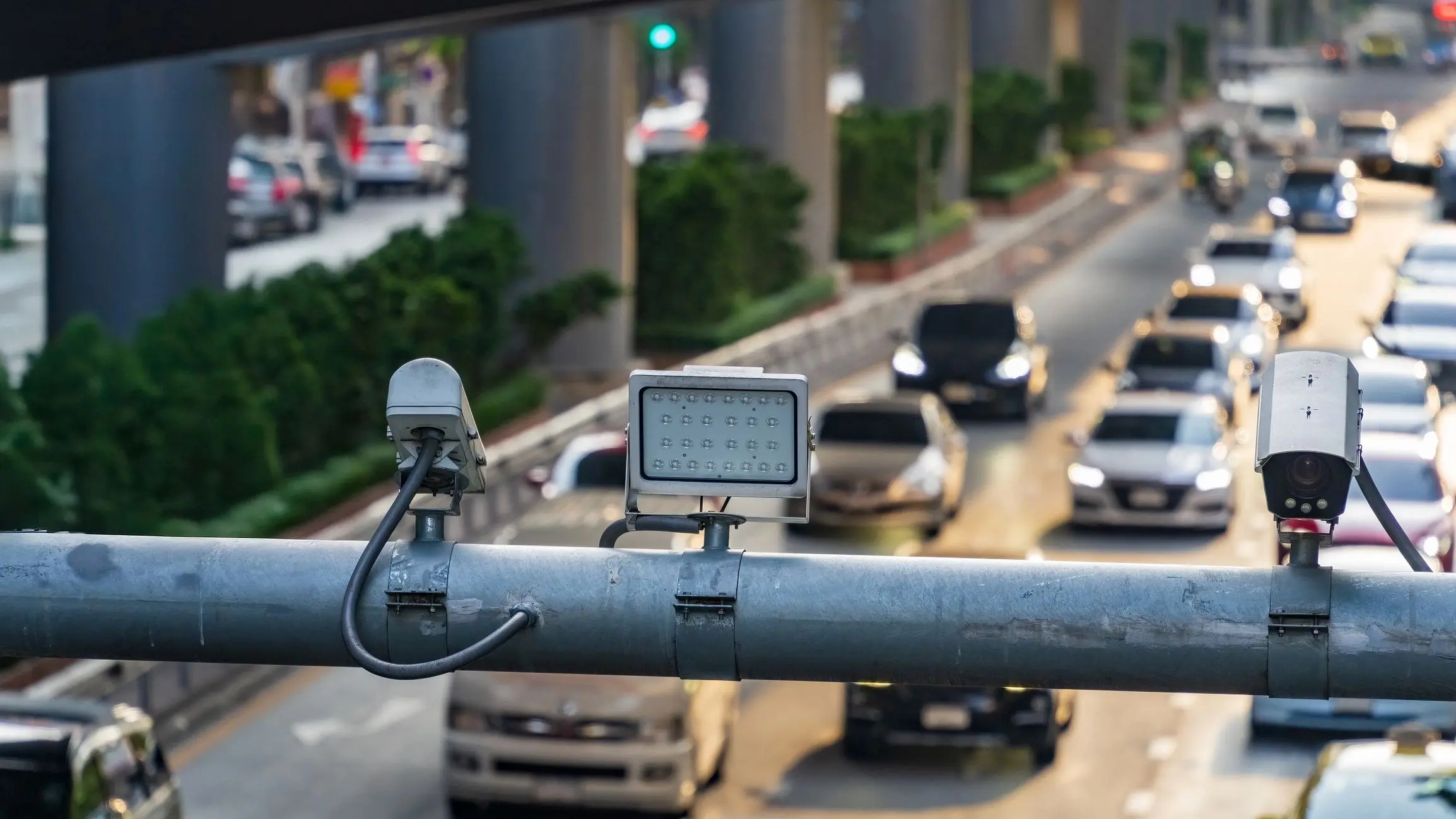 Traffic cameras monitoring busy urban road.