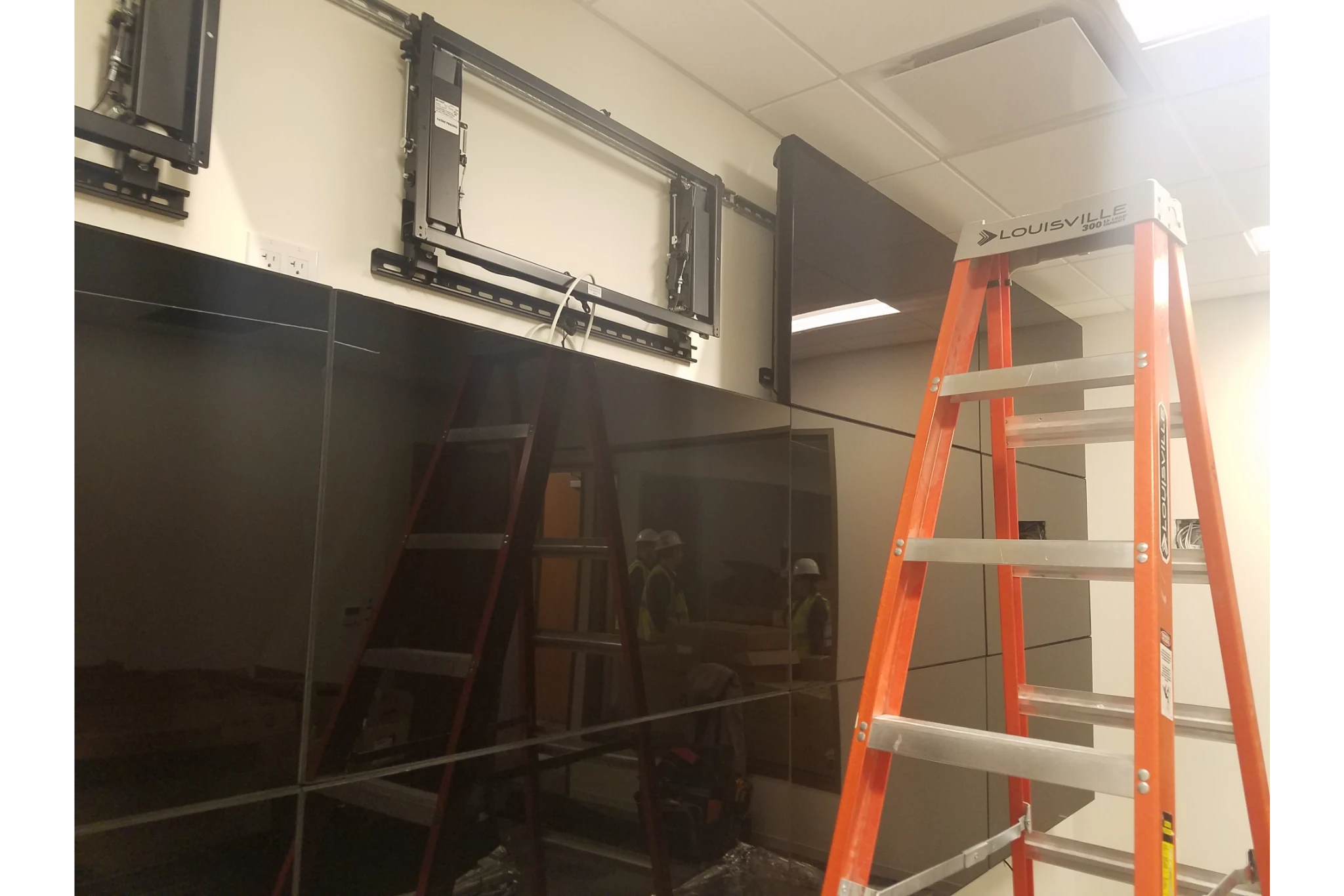 Orange ladder near wall-mounted flat-screen TVs