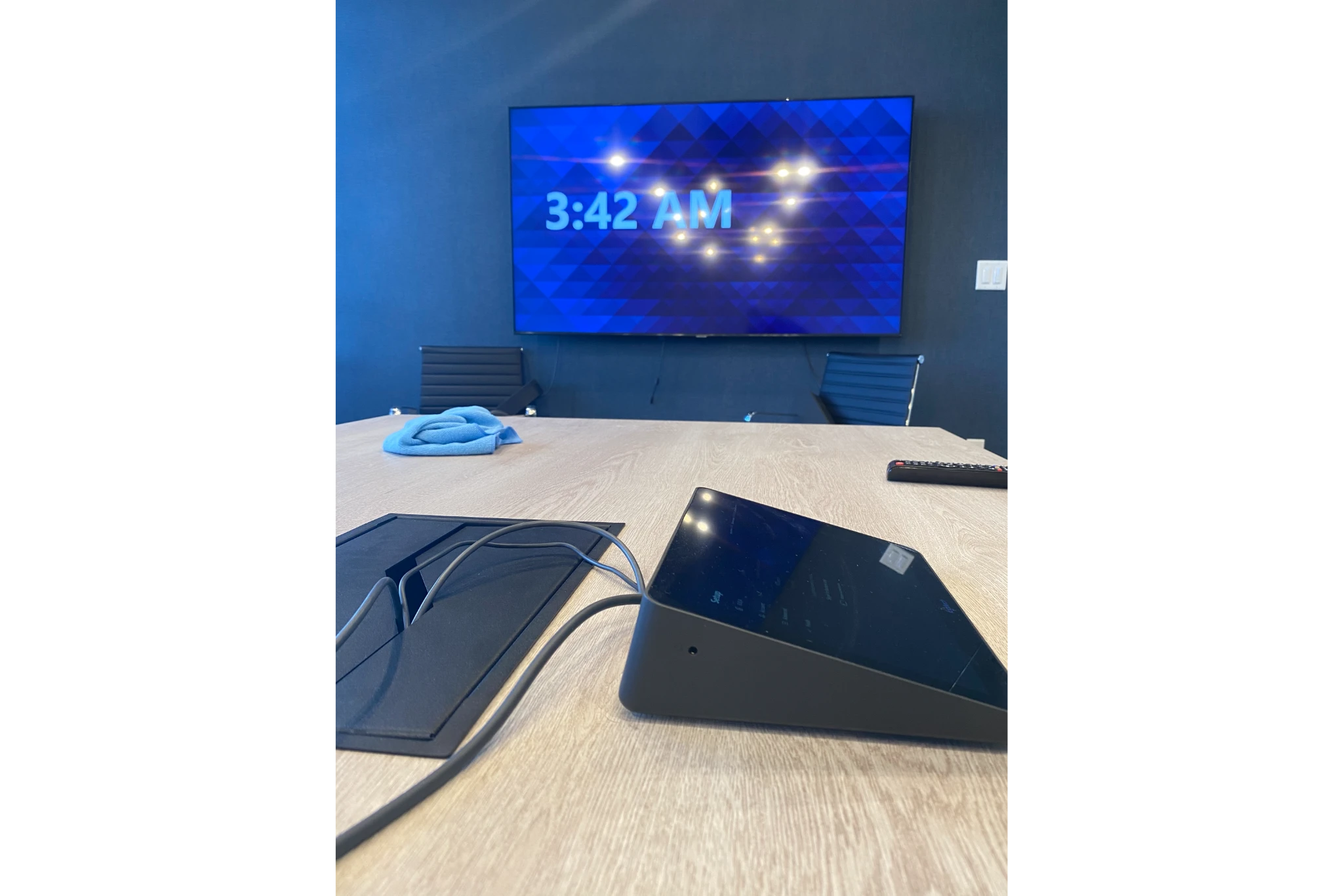 Empty conference table, screen displaying 3:42 AM