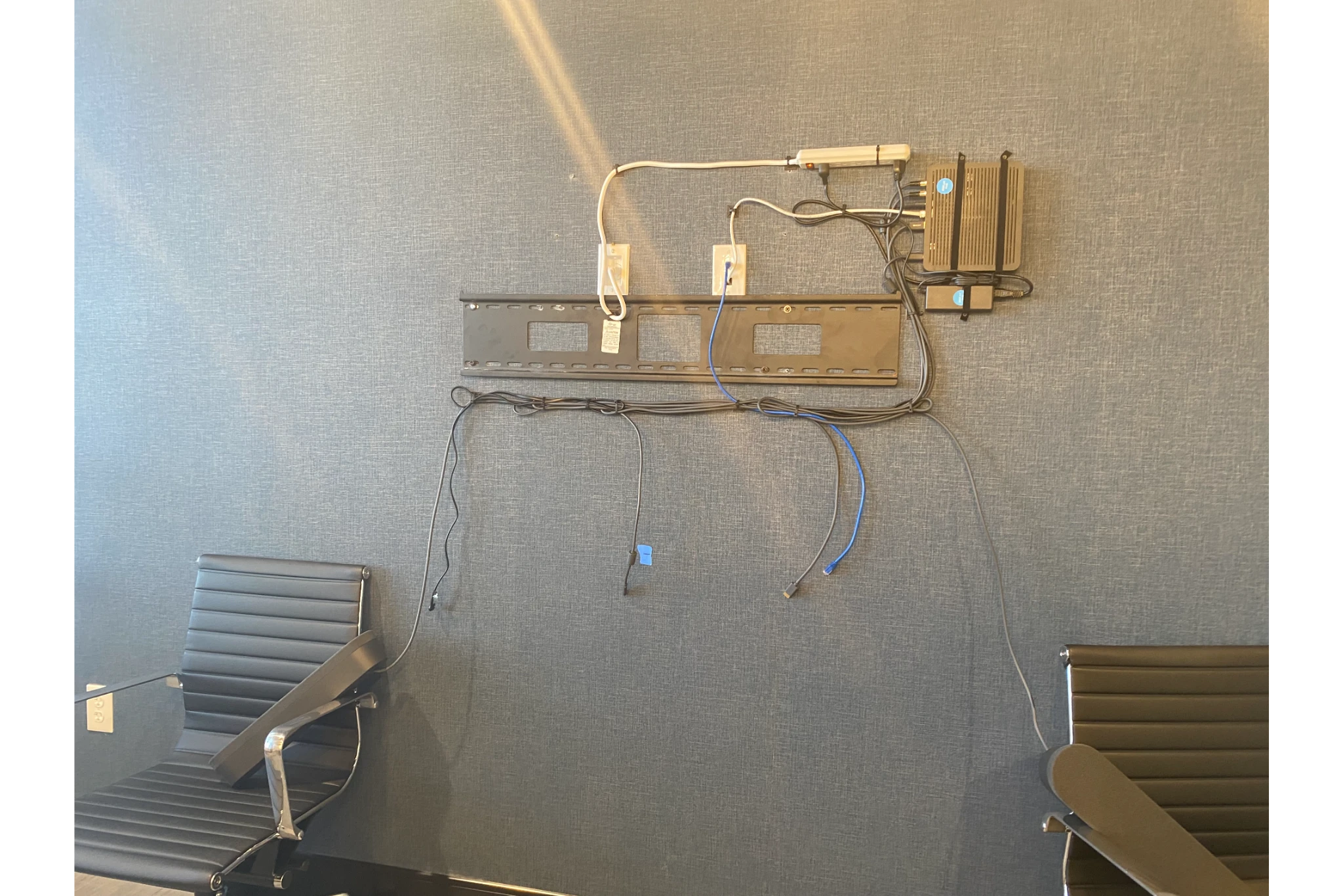 Wall TV mount with dangling cables and chairs