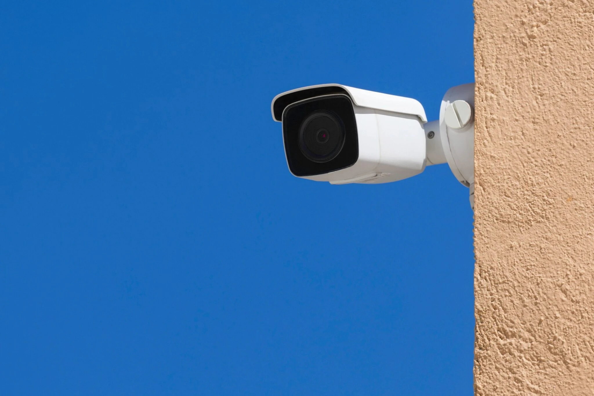 White outdoor security camera on stucco wall