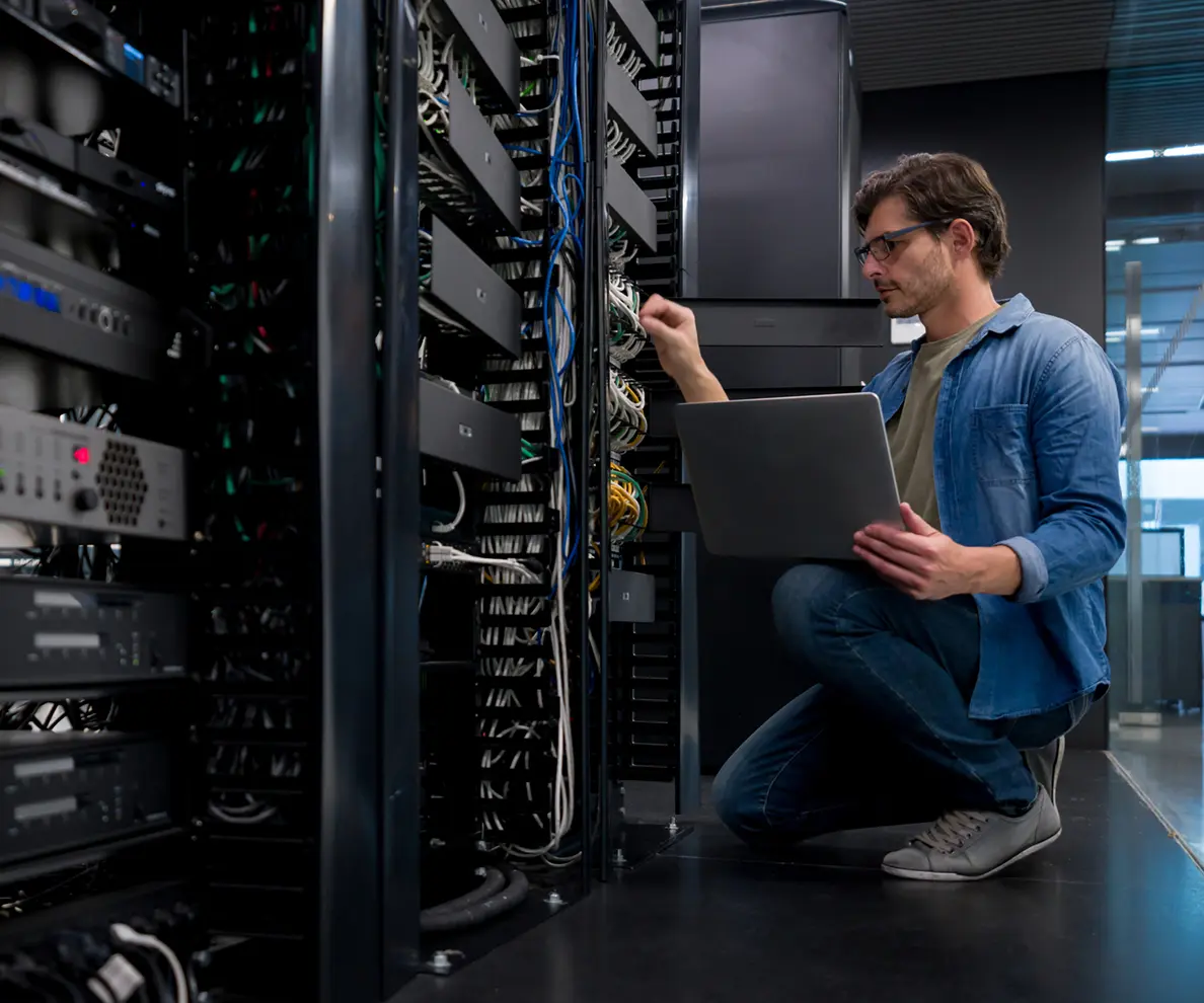 IT technician repairing server rack with laptop